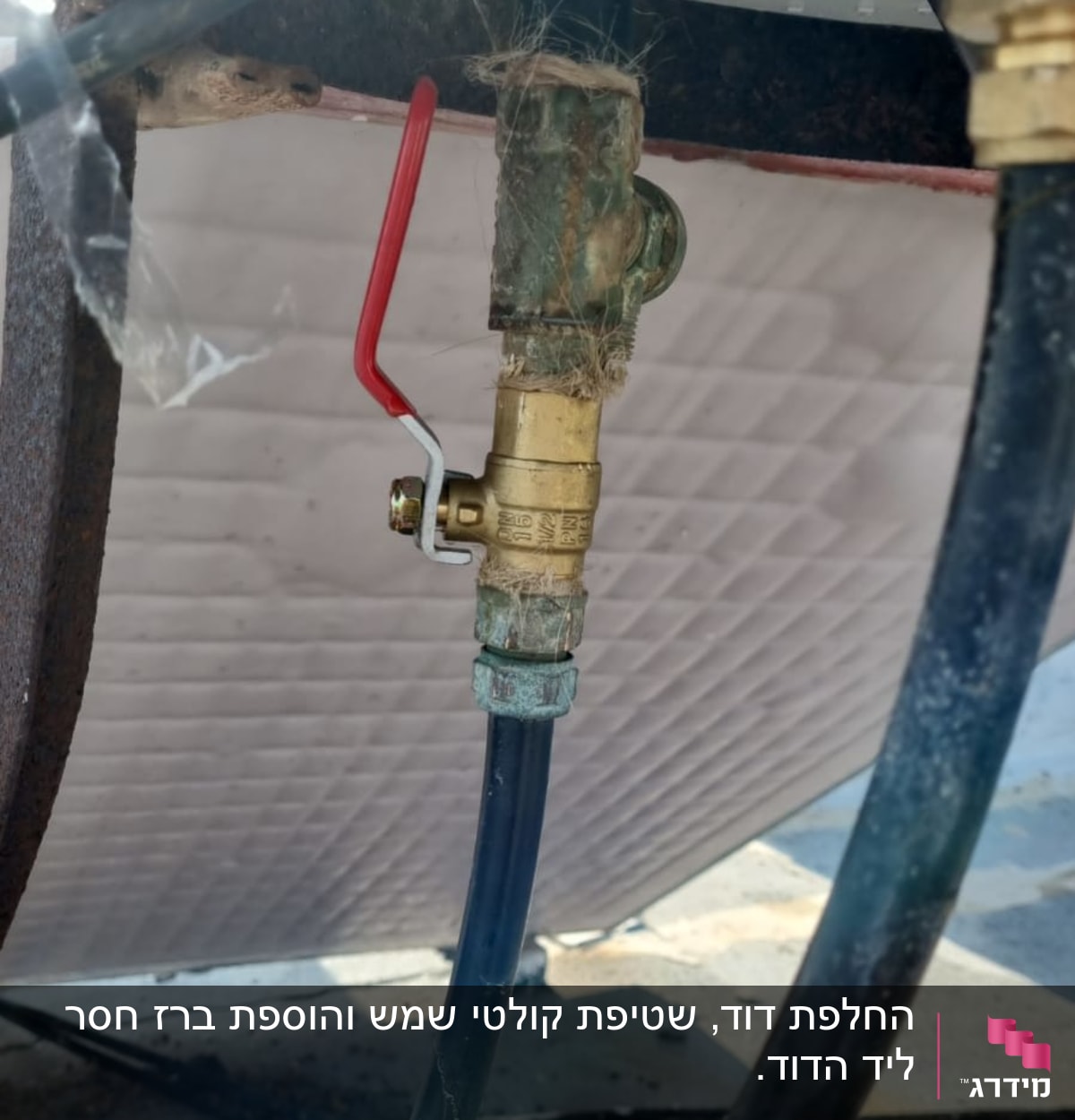 שסתום מתכת עם ידית אדומה בצינור דוד שמש